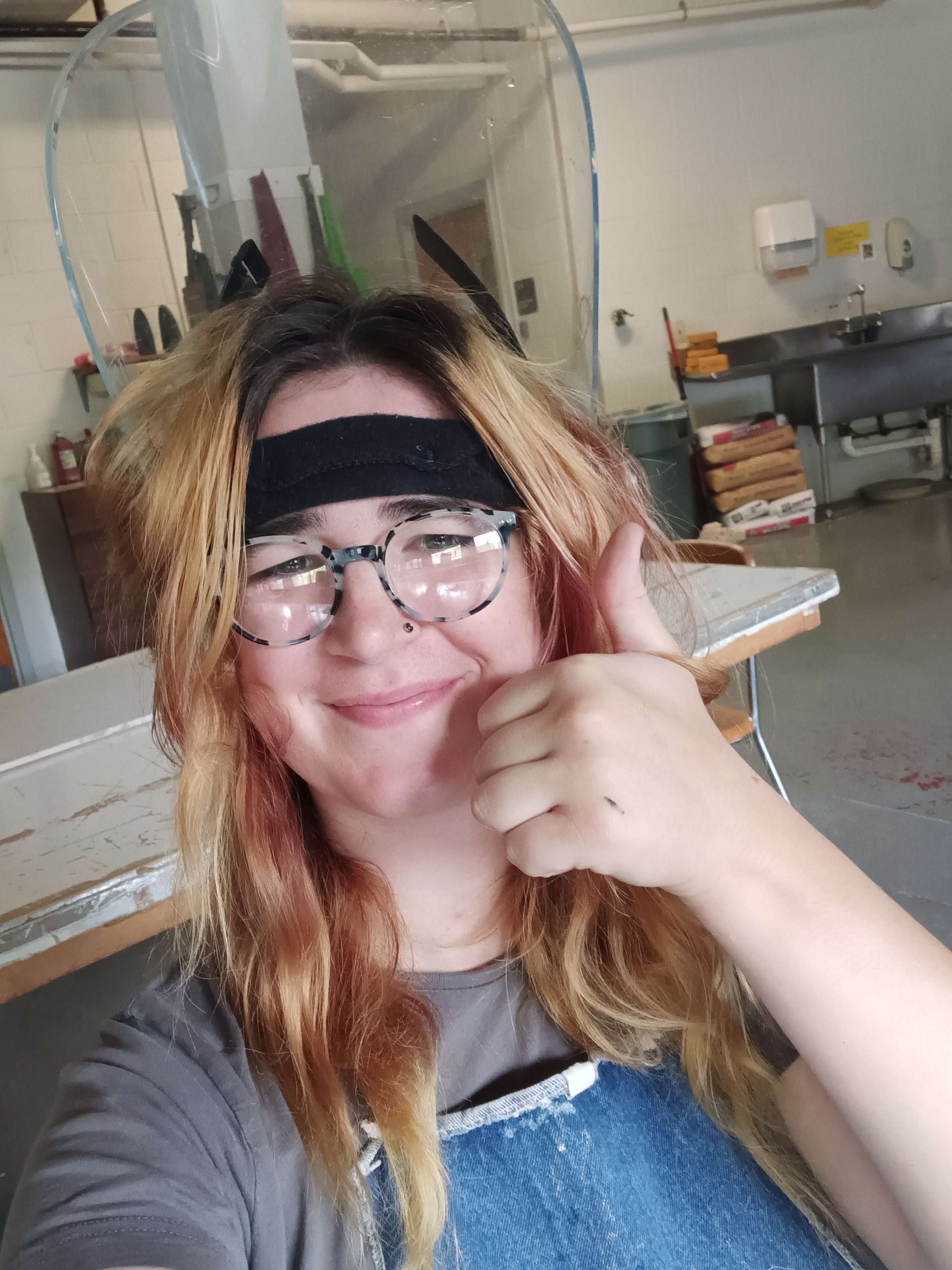 Joanie wearing a protective face shield and giving a thumbs up